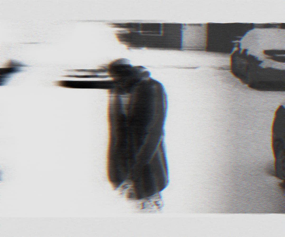Alpha The Wolf walking through a parking lot in a long coat, shot with heavy horizontal motion blur and trailing ghost images, environment barely legible