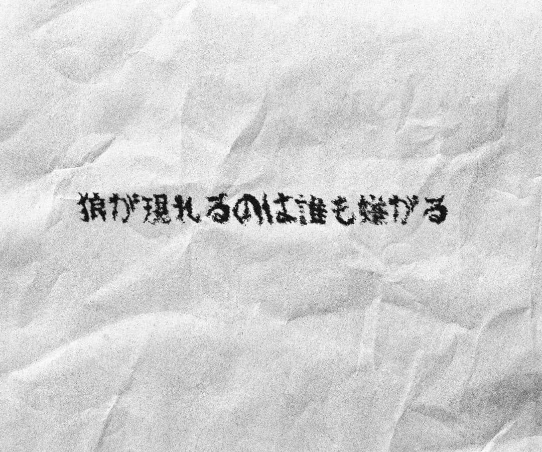 Nobody Likes When a Wolf Shows Up — Japanese kanji translation of the title in the same Gothic hand-drawn style on crumpled white paper
