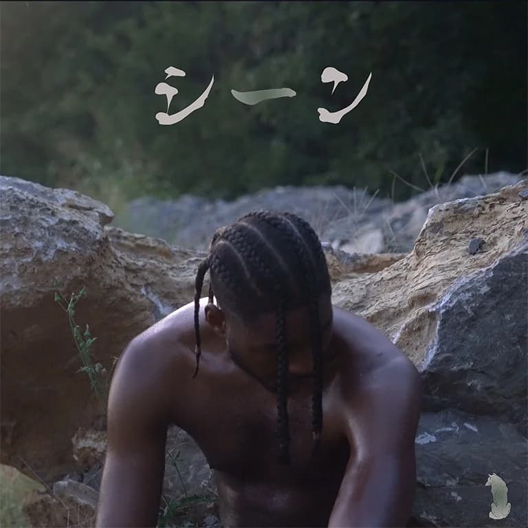 Alpha The Wolf shirtless with braids, head bowed forward among large rocks and dense green foliage with Japanese katakana in the upper left — Scenes official cover