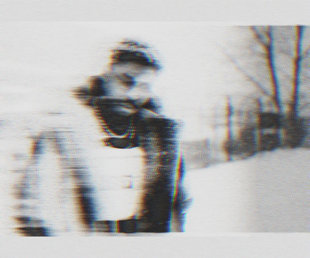 Alpha The Wolf hunched forward in a heavy coat outdoors in the snow, shot with extreme horizontal motion blur and chromatic aberration, figure fragmenting across the frame