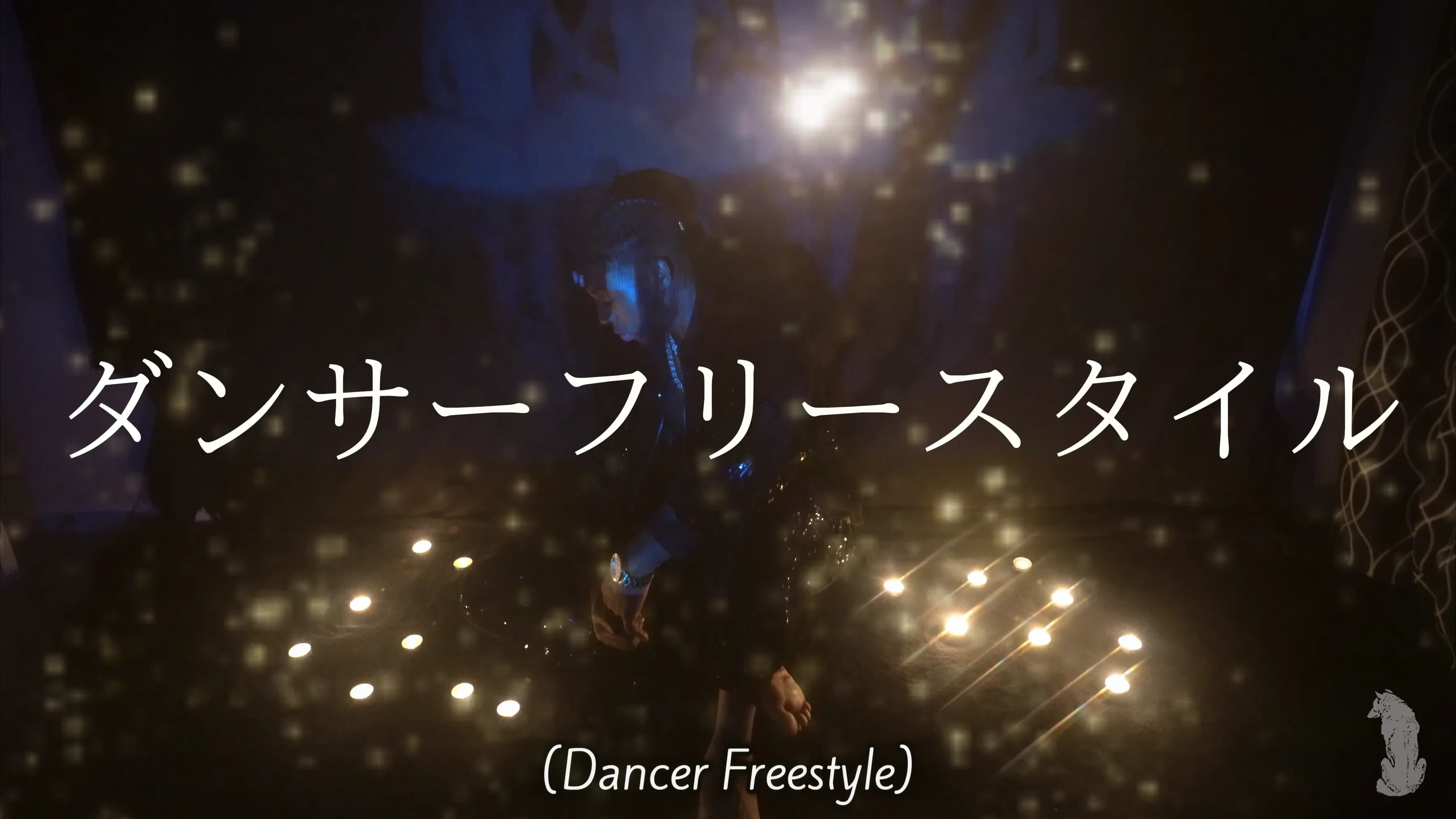 A candlelit title card for the Dancer Freestyle visual, Alpha The Wolf barely readable through a dense veil of blue and gold bokeh with two clusters of floor candles glowing at the base of the frame.